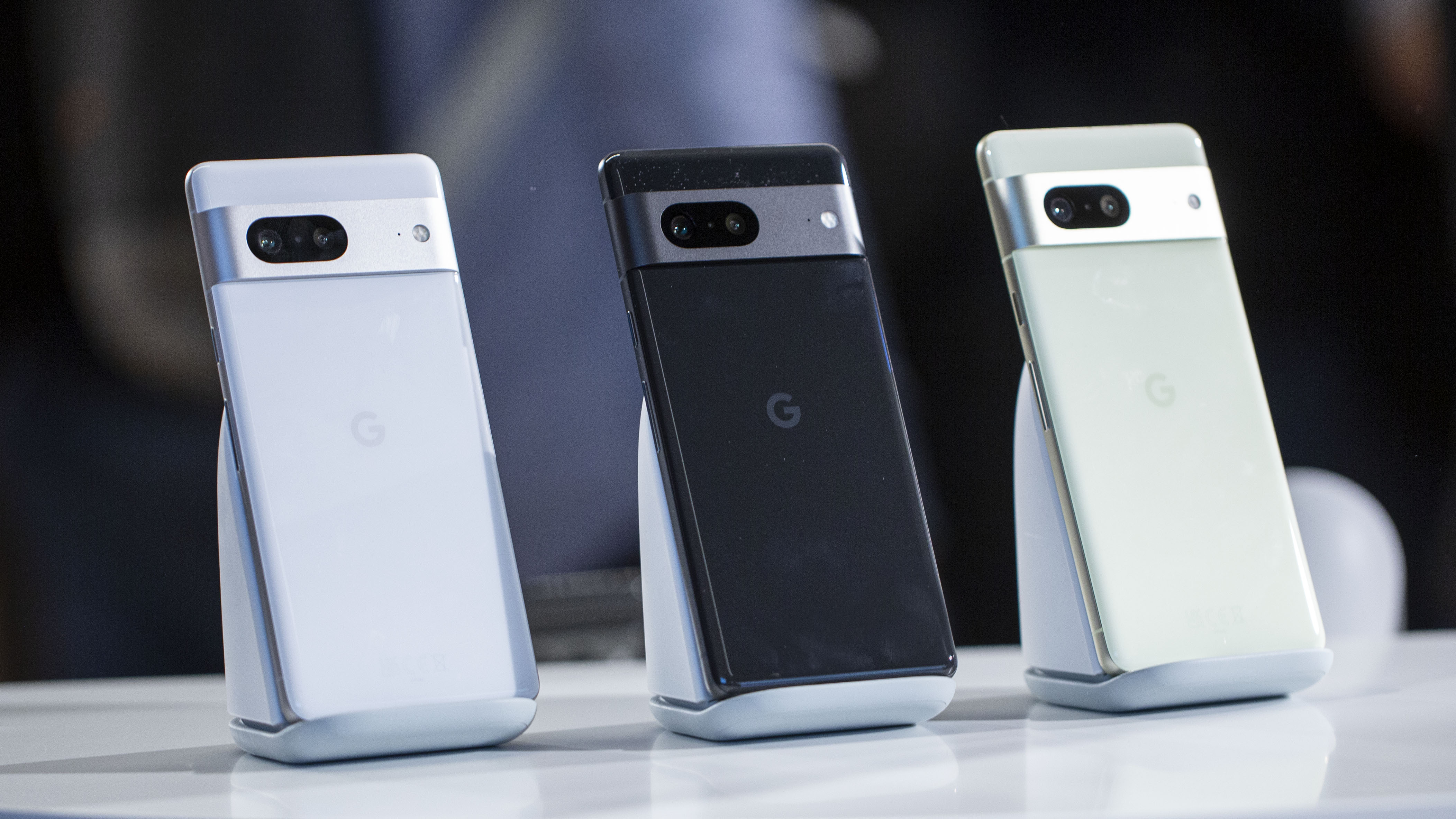  Three Google Pixel 9 Pro Fold smartphones in white, black, and green colors are displayed on podiums against a blurred background.