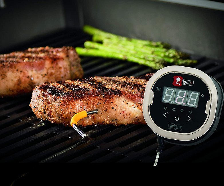 Fleisch auf einem Grill, daneben das Grill-Thermometer von Weber